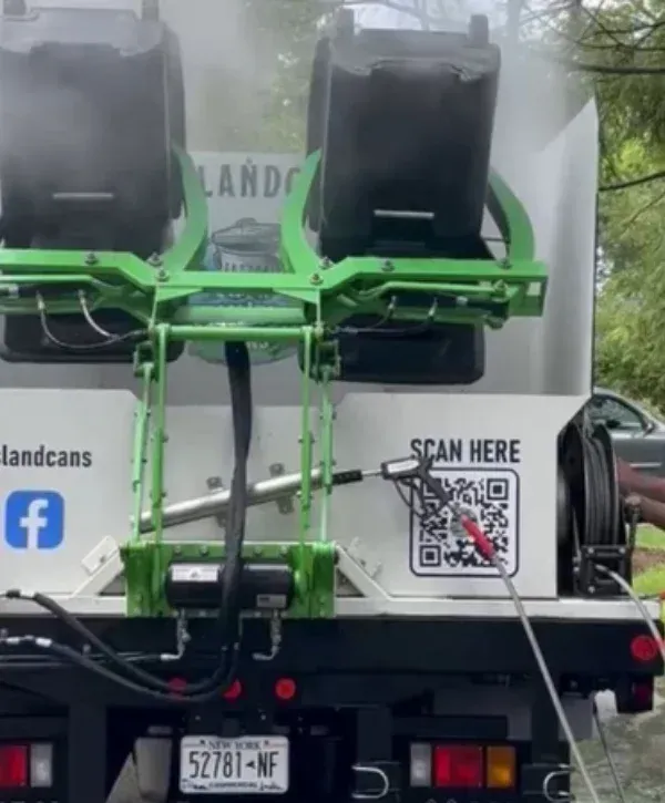 Automated trash can cleaning truck using high-pressure system to sanitize bins 