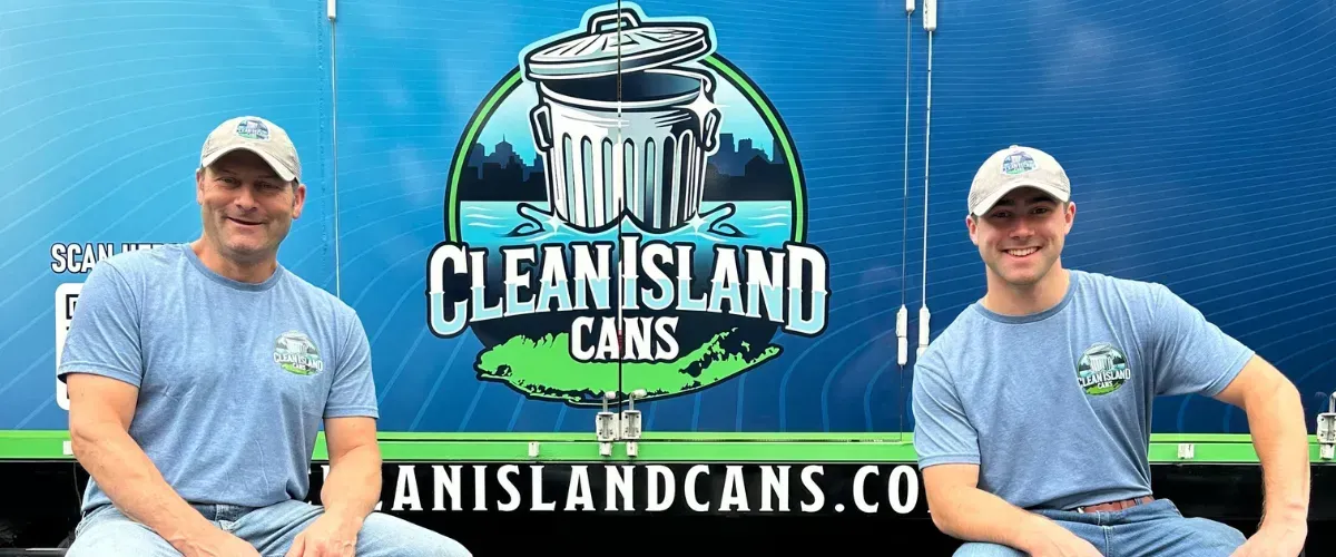 Two Clean Island Cans team members sitting in front of a company truck displaying the Clean Island Cans logo.