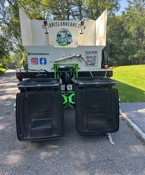 Garbage can cleaning truck rear view with two residential trash bins mounted for cleaning
