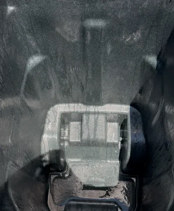 Inside view of a large, dark gray recycled bin with light water stains and residue on its textured plastic surface.
