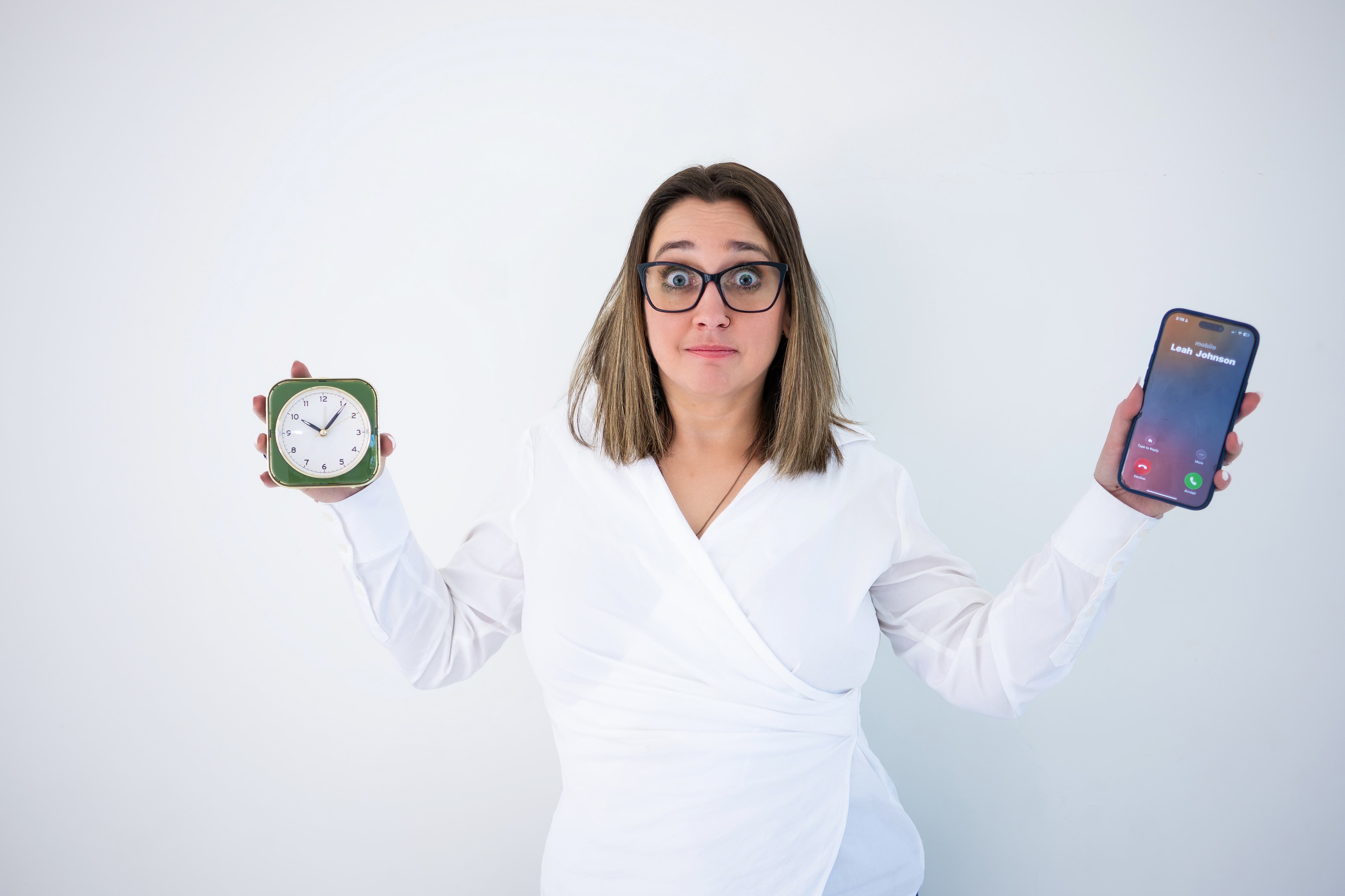 Business owner holding a phone next to a clock, representing invoicing, payment reminders, and getting paid faster