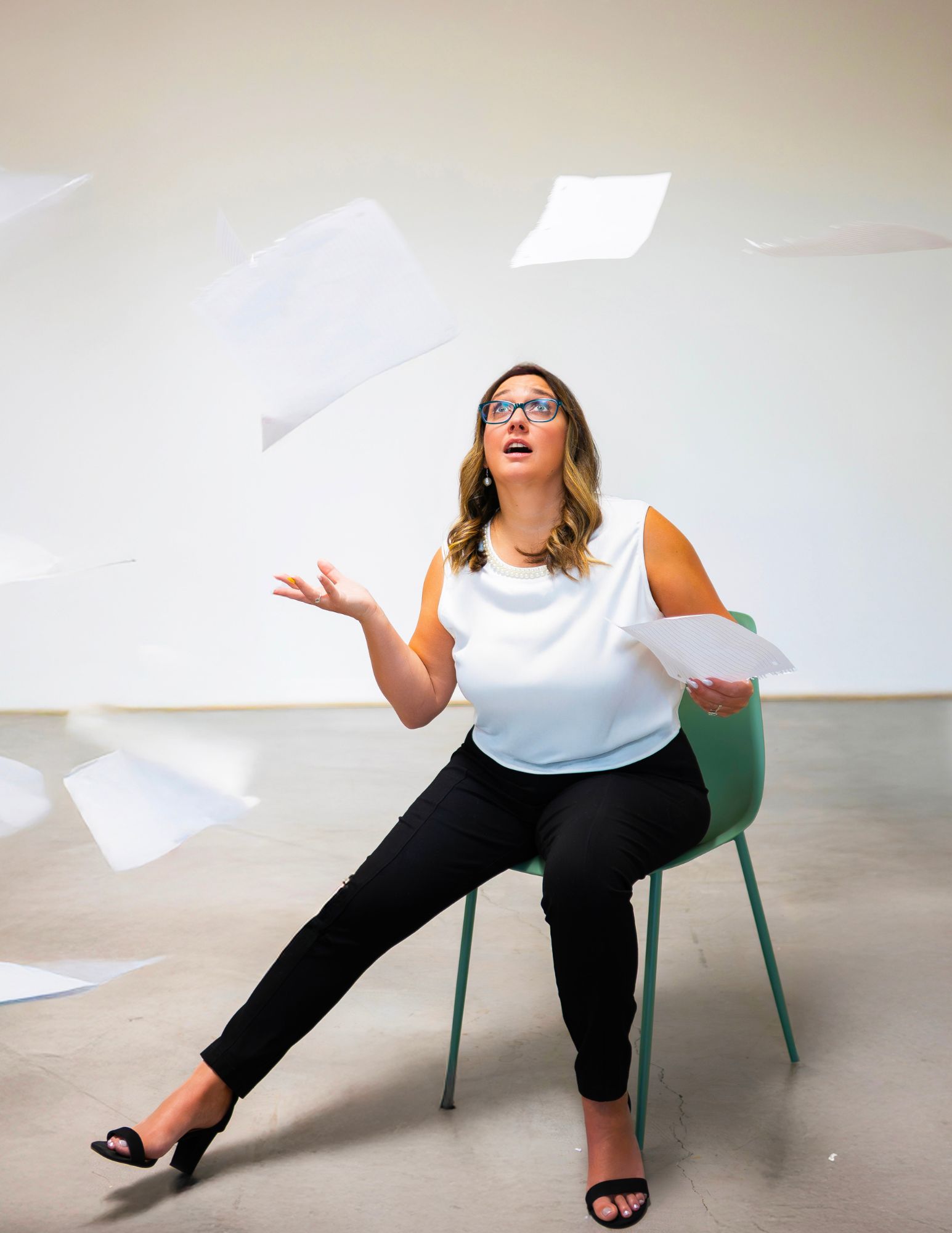 Business owner sitting in a chair throwing papers into the air, illustrating bookkeeping frustration and financial overwhelm.