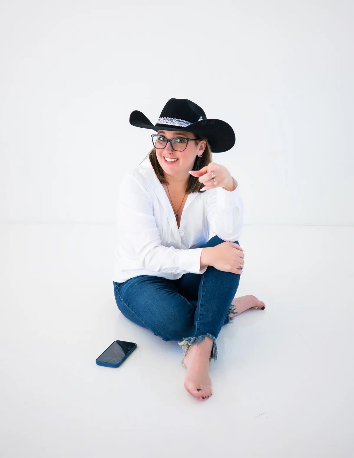 Business owner sitting on the ground with a phone beside her while taking time for a mid-year financial reset and reviewing her bookkeeping and financial records.