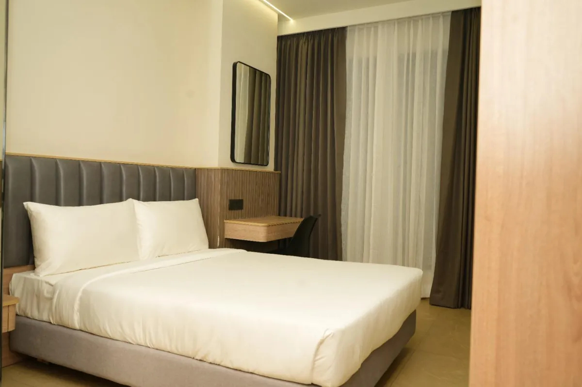 Deluxe Room interior with king-size bed, seating nook and calm street view.