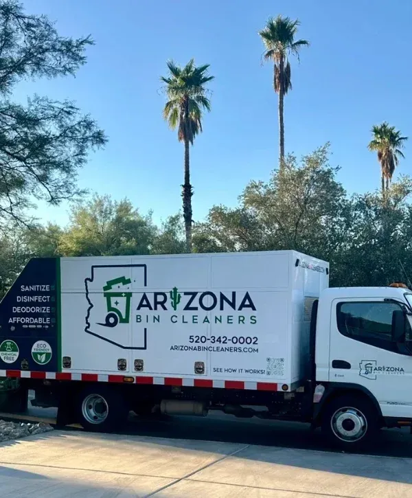 A bin cleaning service truck with 'Arizona Bin Cleaners' branding and two green trash cans in front of a modern desert home.
