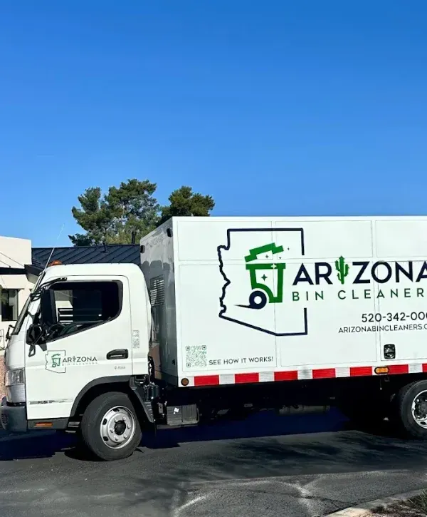 A bin cleaning service truck with 'Arizona Bin Cleaners' branding and two green trash cans in front of a modern desert home.