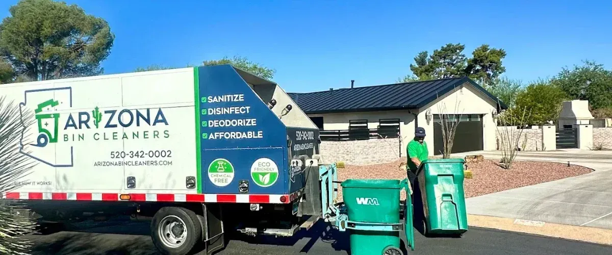 An Arizona Bin Cleaners truck lifts two bins in front of a modern house with cactuses and mountains in the background.