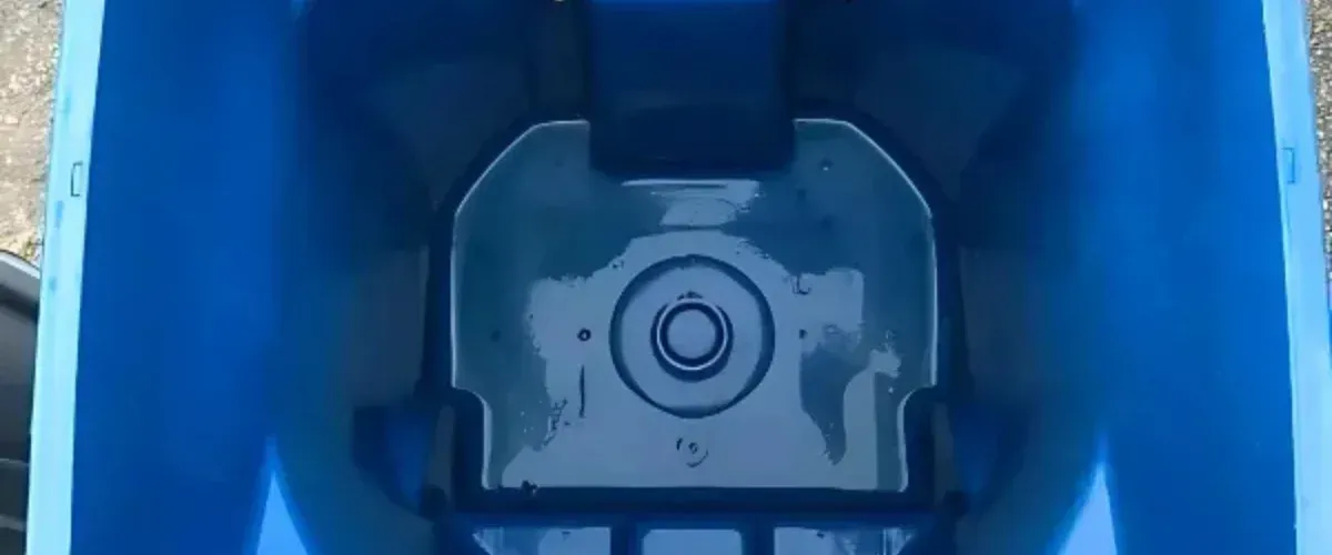 A close-up, top-down view of the interior of a blue plastic container with a circular drain at its bottom.