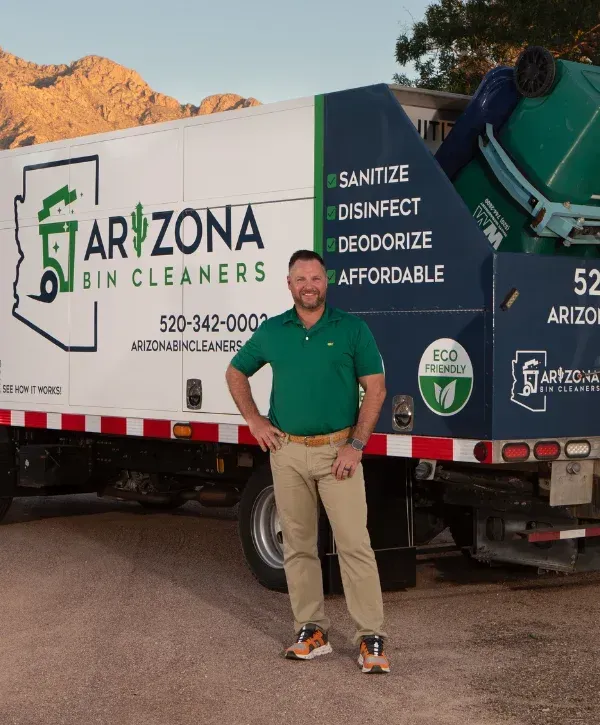 A smiling man in a green polo shirt stands confidently beside an Arizona Bin Cleaners truck with mountains in the background.