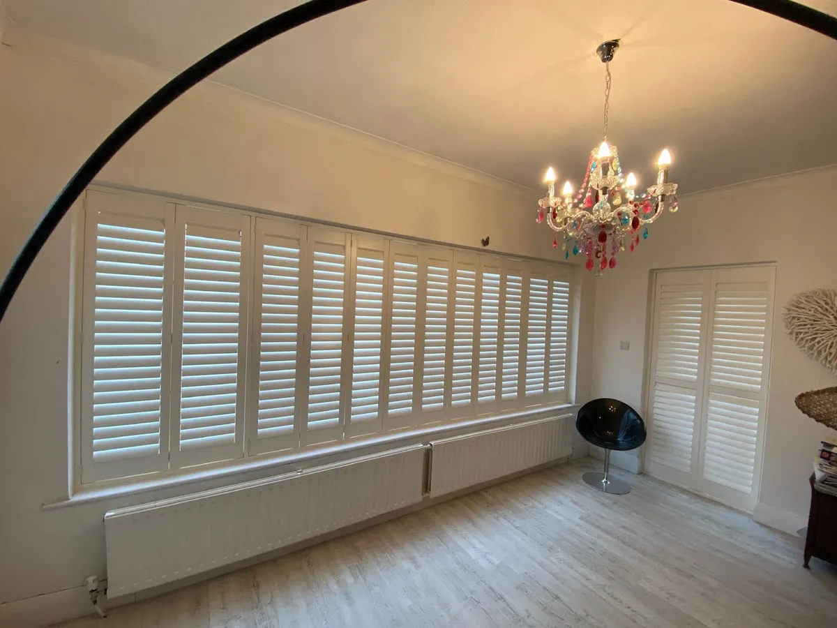 Full height shutters across a wide bedroom window