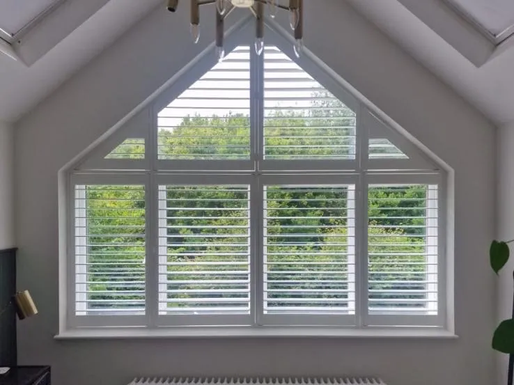 White shutters fitted to a gable window in a loft bedroom