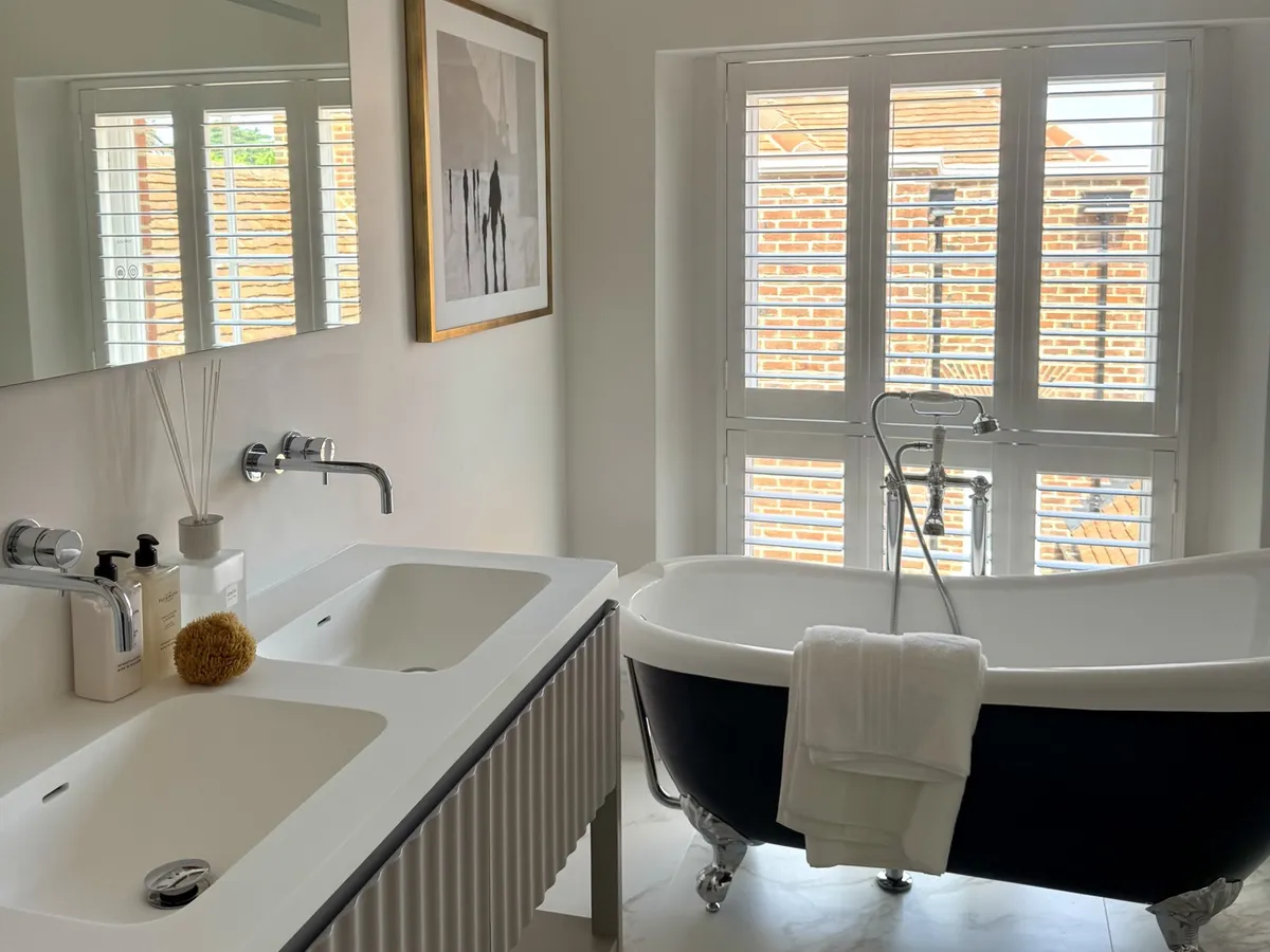 Bathroom plantation shutters giving privacy above a roll-top bath