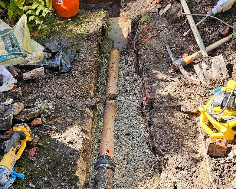 Excavation work to replace blocked drains in Bournemouth, showing new drainage pipe installation alongside professional groundworks