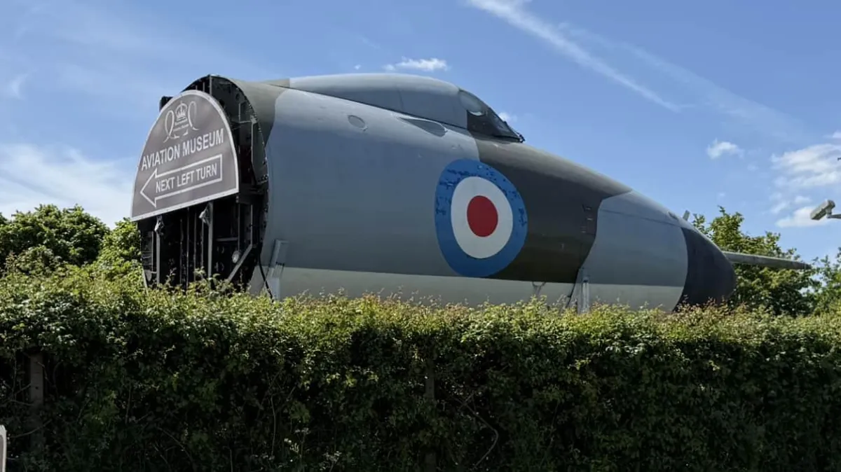 Based on the image you've shared, here's the alt text: "RAF aircraft display at Bournemouth Aviation Museum with RAF roundel markings visible through hedgerow.