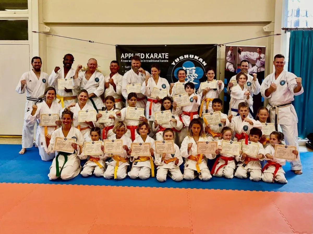A photo of Sam and his karate students holding certificates