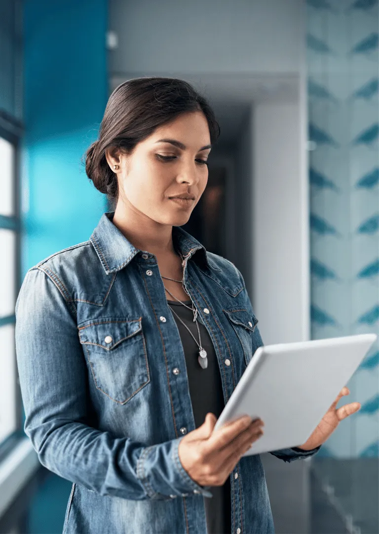 woman in jeans jacket holding a tab