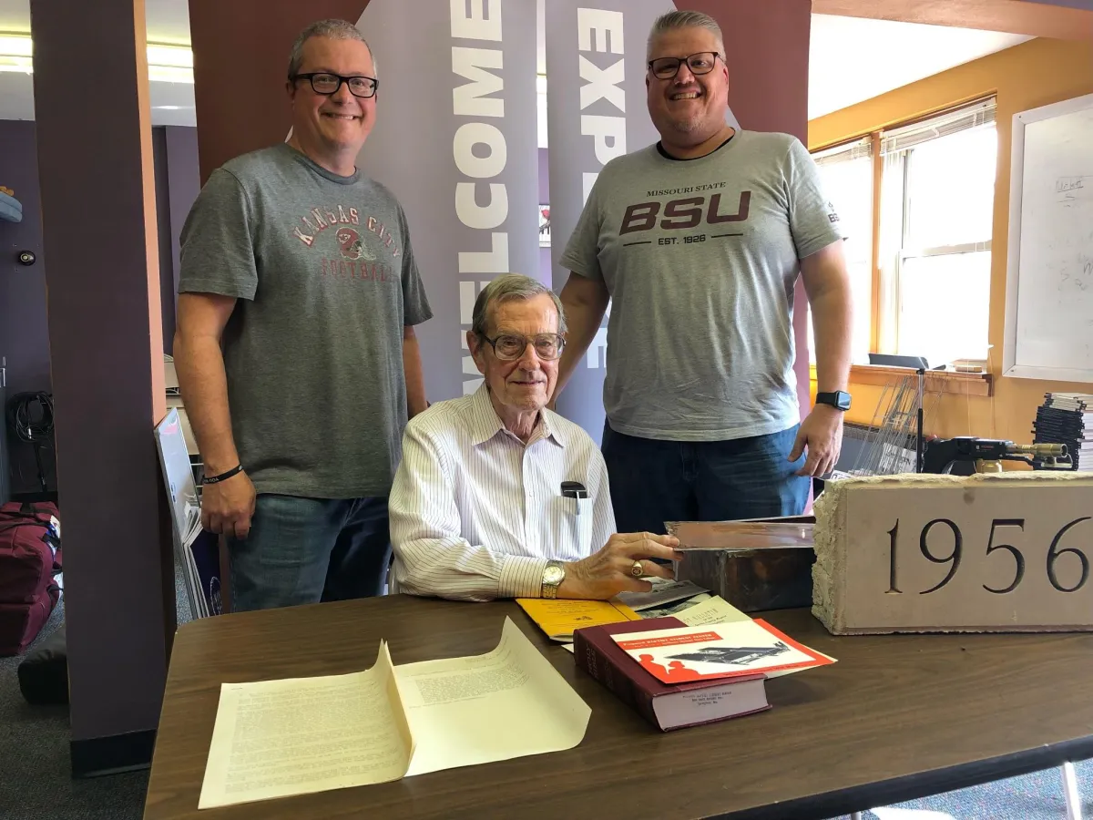 a city street at night with a tall building in the background