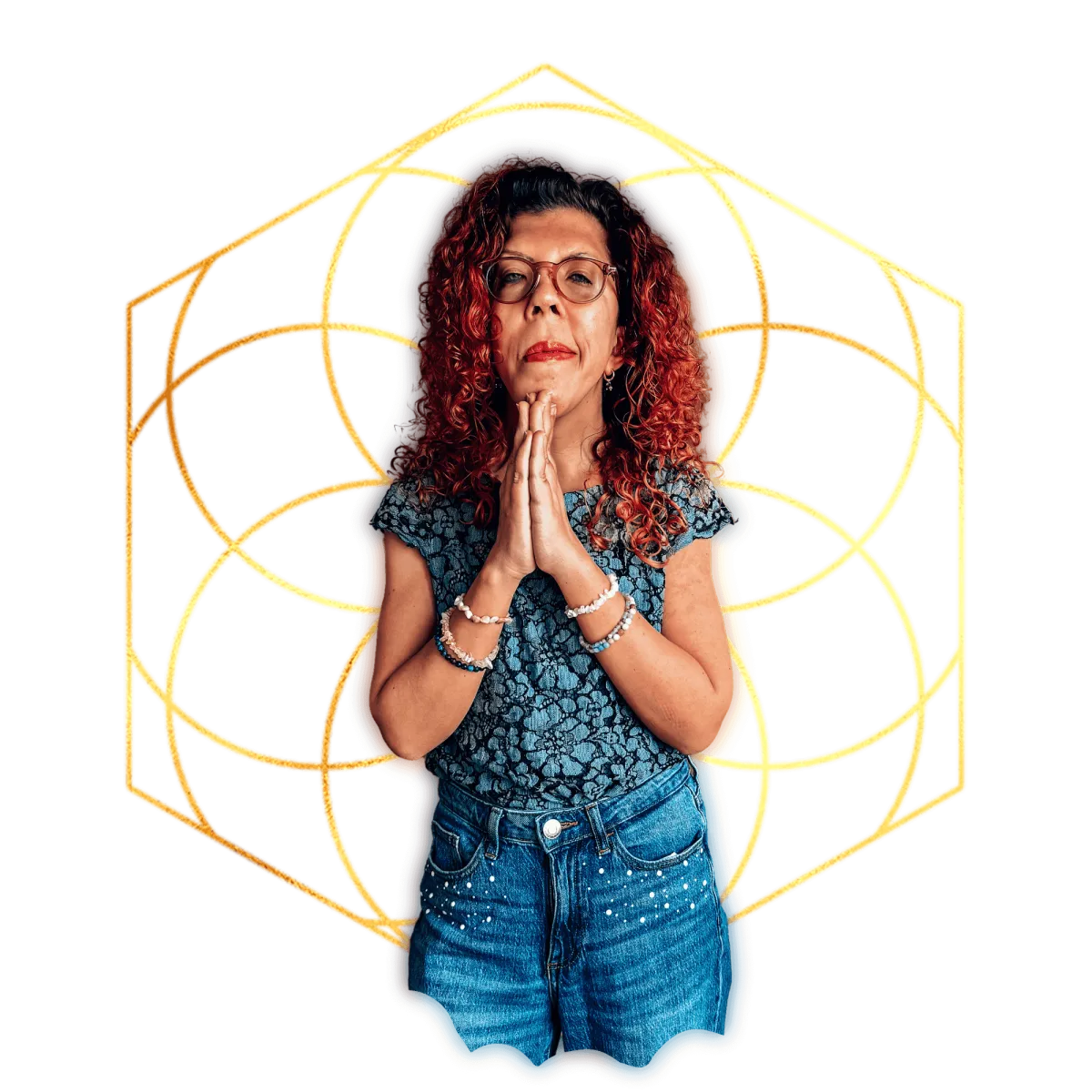 Hellig geometrisk symbol i gull. Kvinne med krøllete, rødt hår. Holder hendene samlet i en namaste-hilsen. Dongeribukse (jeans) + en blå blondetopp er dagens antrekk. Smil og krystallarmbånd..