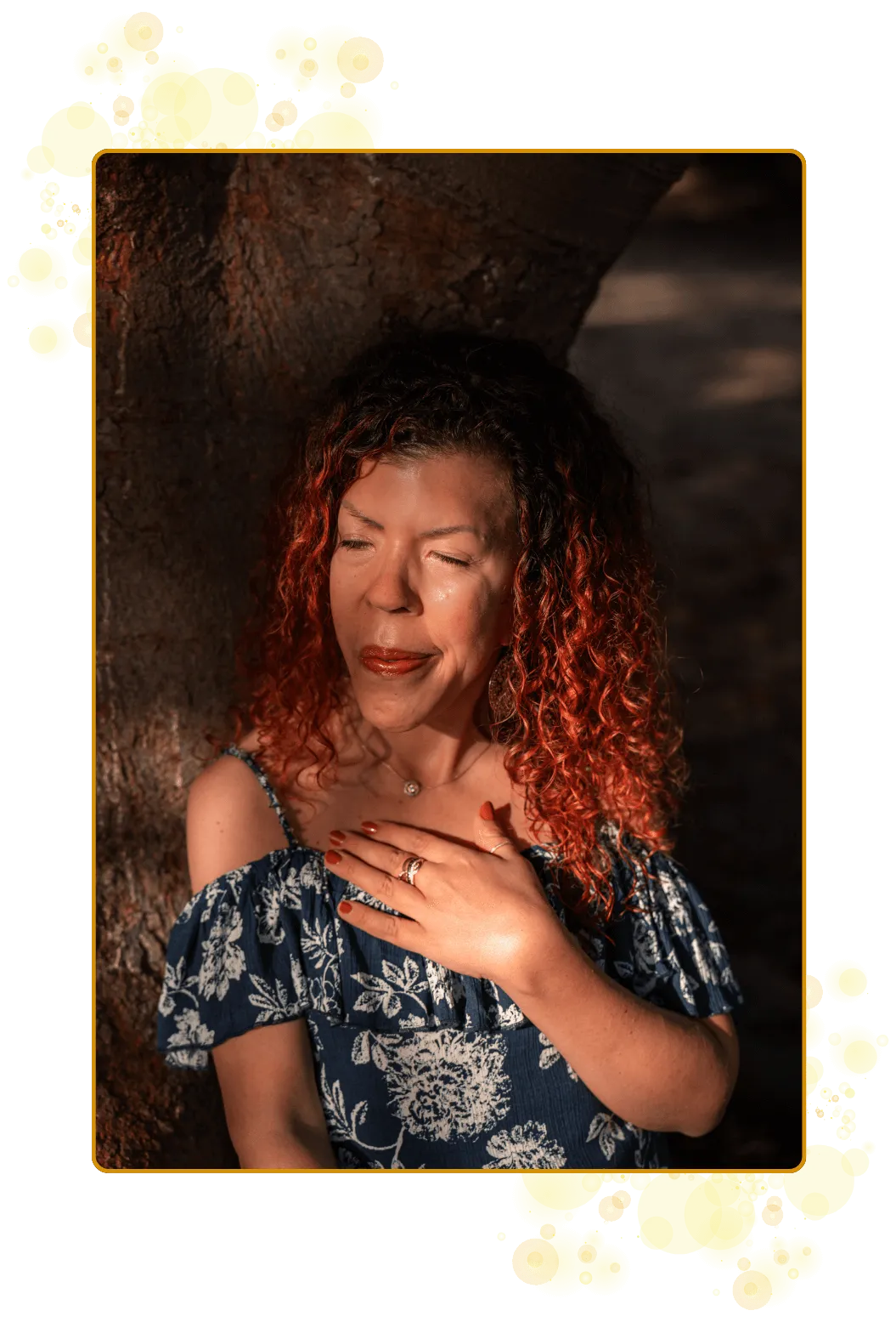 En kvinne, søster, prestinne som bærer et ekspanderende og magisk felt sammen med Universet. Et lunt og varm smil, rødt og krøllete hår, kjole i mørkeblått og hvitt. Avslappet, i ett, i kraften av alt hun er. Liggende på en rot og lent inntil treets stamme.