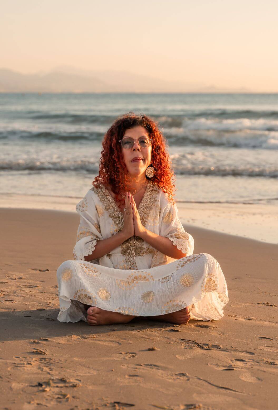 A woman in prayer at the beach at sunrise. Devoted to Spirit, Universe and the magic within.