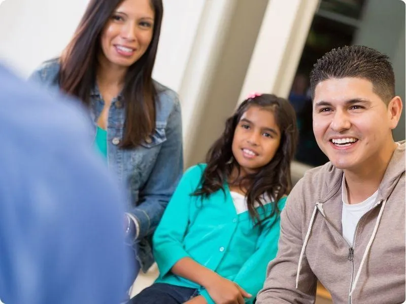 woman, girl and man all sat smiling at a teacher