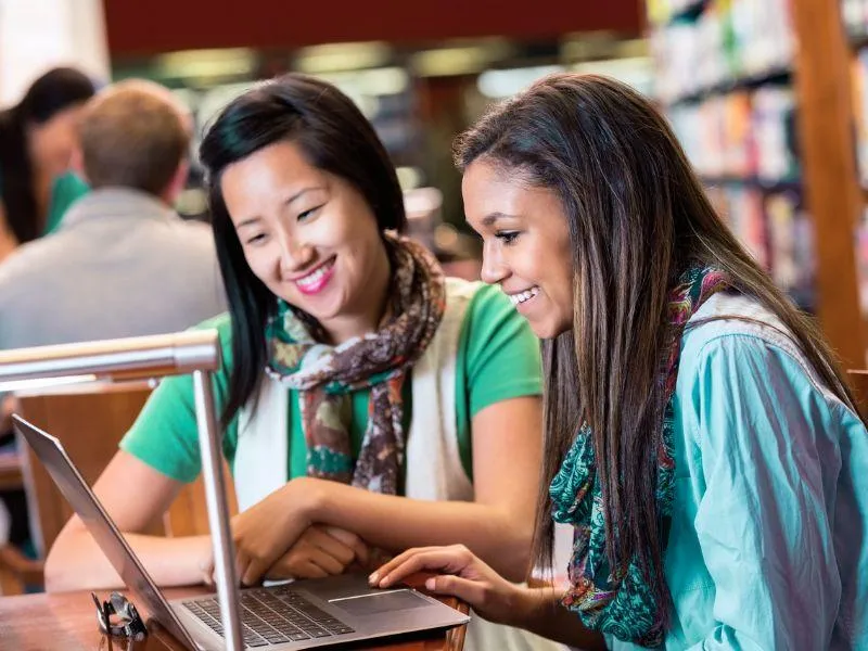 two female tutors sitting at laptop learning together