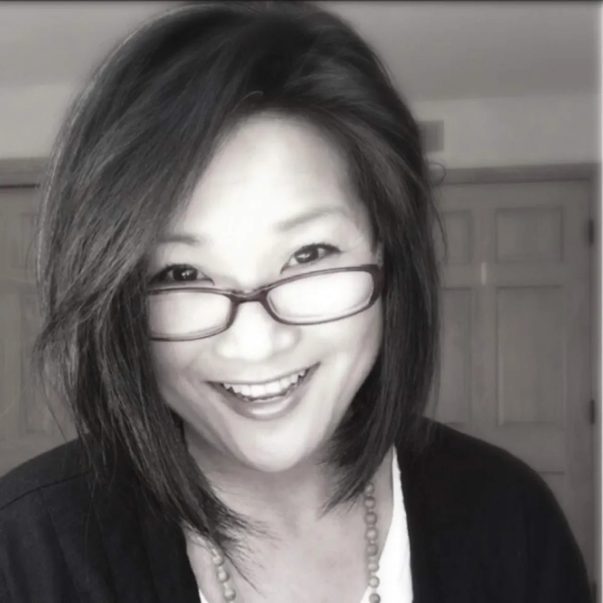 A Smiling women with shoulder-length dark hair and a casual black cardigan