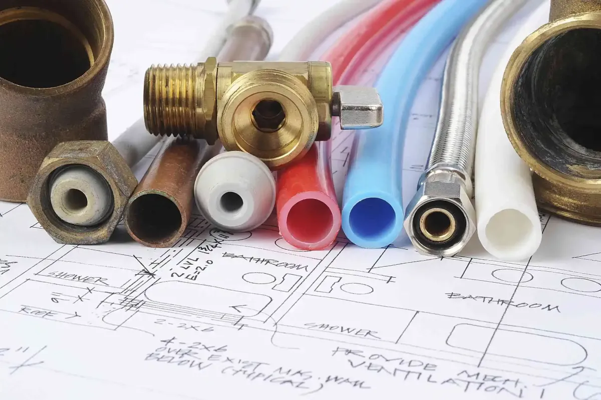 Close-up of outdated lead, polybutylene, and galvanized water pipes next to plumbing schematics, ready for replacement.