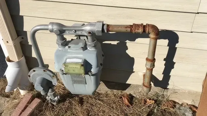 Severely corroded galvanized pipe elbow with mineral buildup and rust, of the gas line by the meter. 