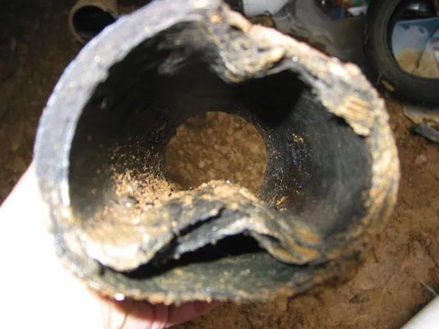 Cross-section of deteriorated Orangeburg pipe collapsed from pressure, blocking all sewer flow.