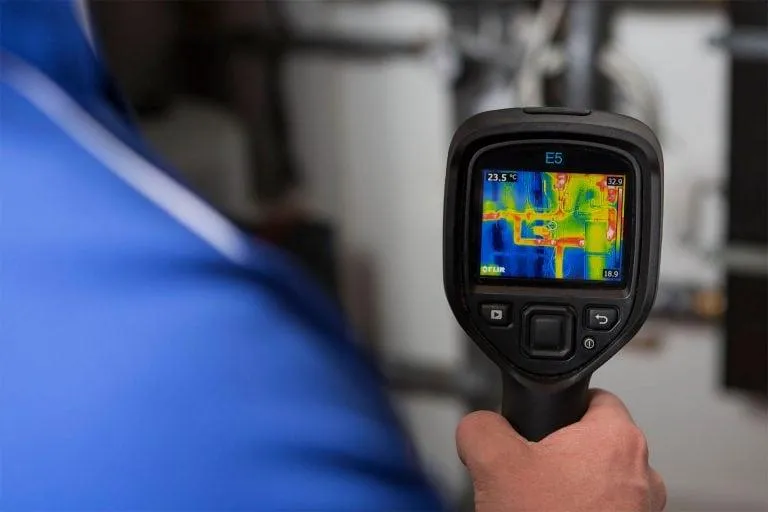 Thermal imaging camera detecting warm spot on hardwood floor—used to locate slab leaks in Victorville homes.
