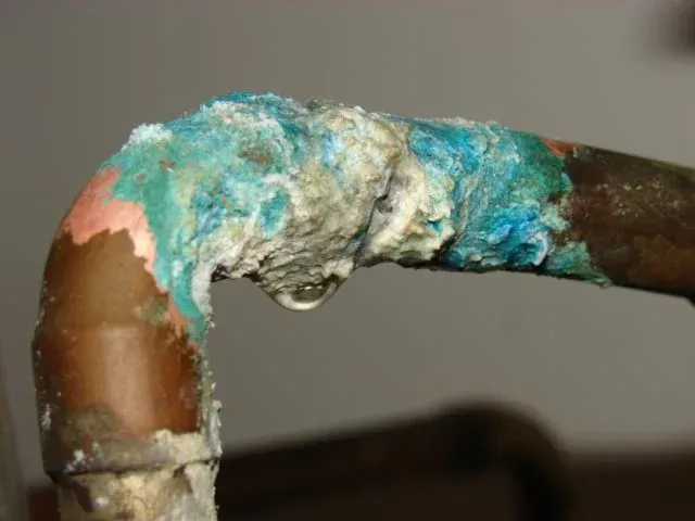 Severely corroded cast-iron sewer pipe with rust and mineral buildup narrowing the flow.