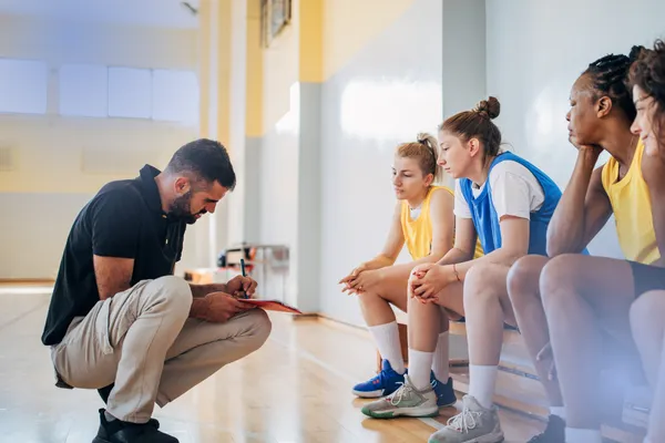 Coach in front of athletes on a sports field, representing leadership in youth sports