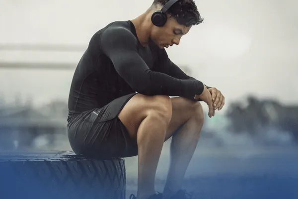 athlete showing athlete burnout signs and symptoms as he sits on the sidelines