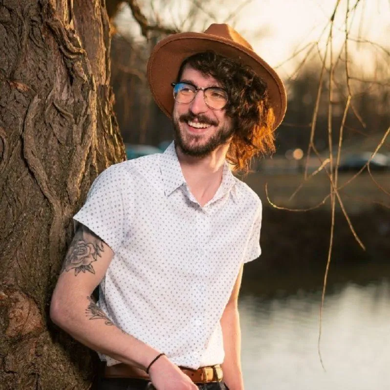 Tiernen Rice, wedding filmmaker and co-founder of Garden of Love Films, holding a camera outdoors during golden hour in Ohio.