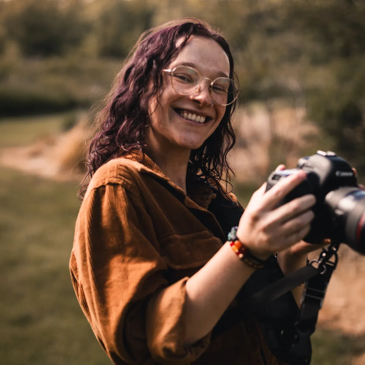 Thistle Rice, wedding photographer and filmmaker with Garden of Love Films, holding a camera during an outdoor session in Ohio