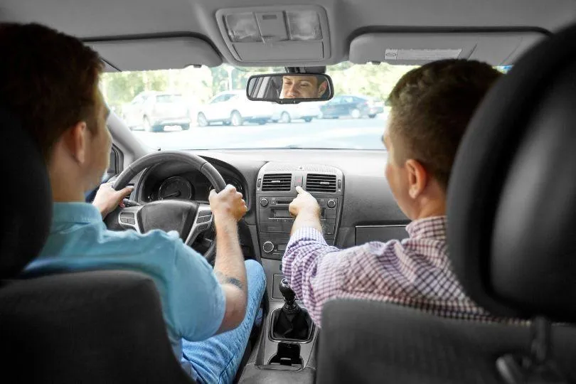 a man sitting in a car with a steering wheel