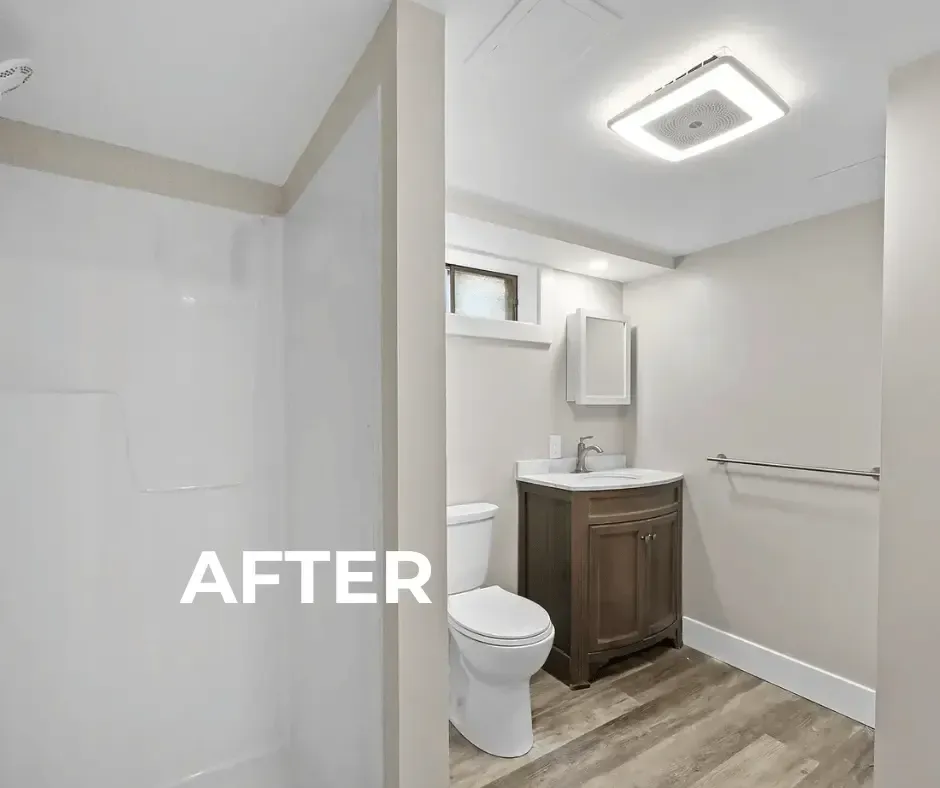 Modern, bright renovated bathroom featuring a new clean white acrylic tub/shower surround, prominent square LED flush-mount ceiling light, refurbished dark wood vanity, and updated window with retained laminate flooring and new light gray paint.