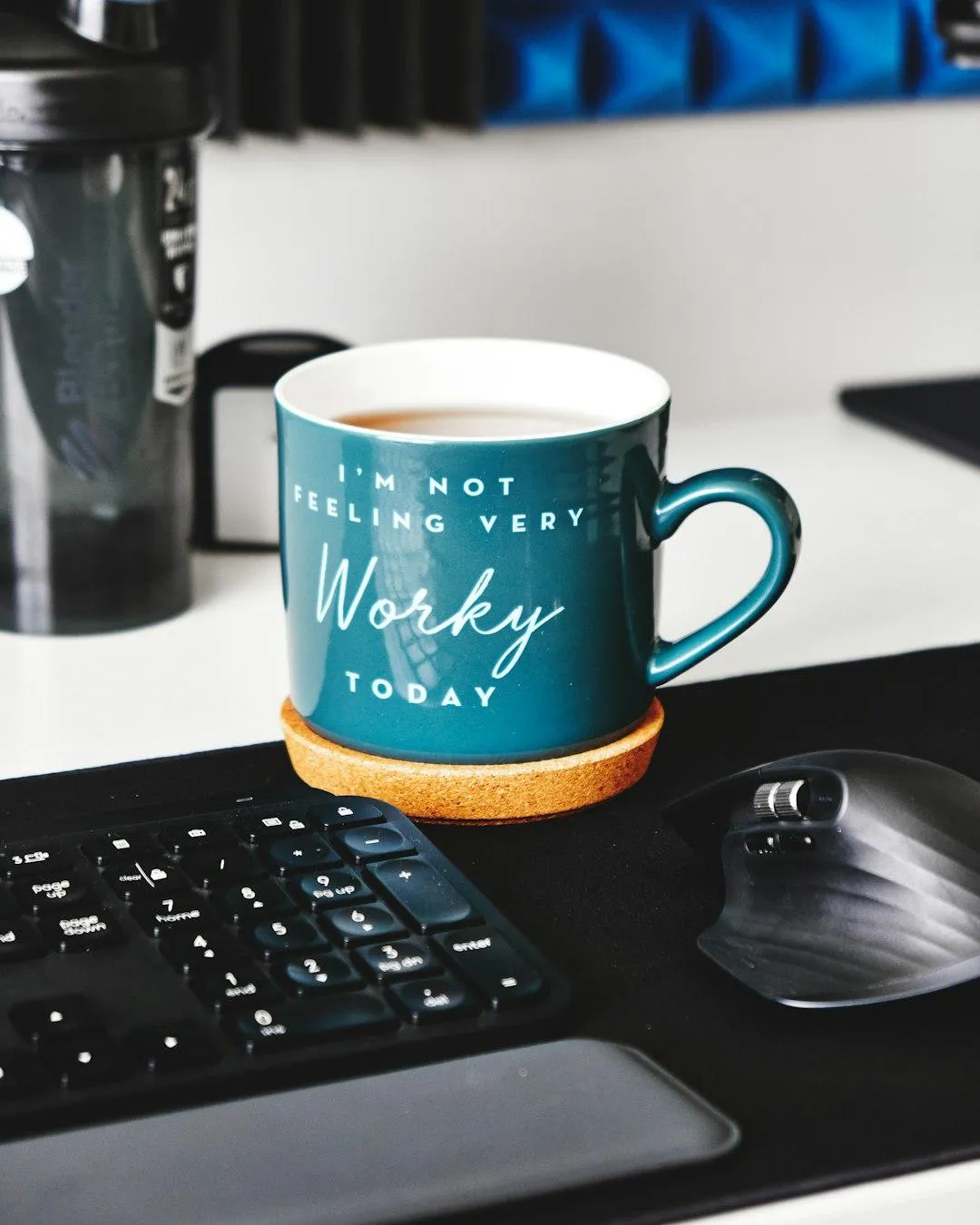 Blue coffee mug beside an open laptop on a home desk.
