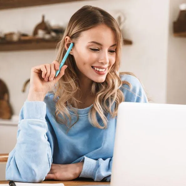 Woman smiling while looking at her laptop, representing learning and developing business acumen.