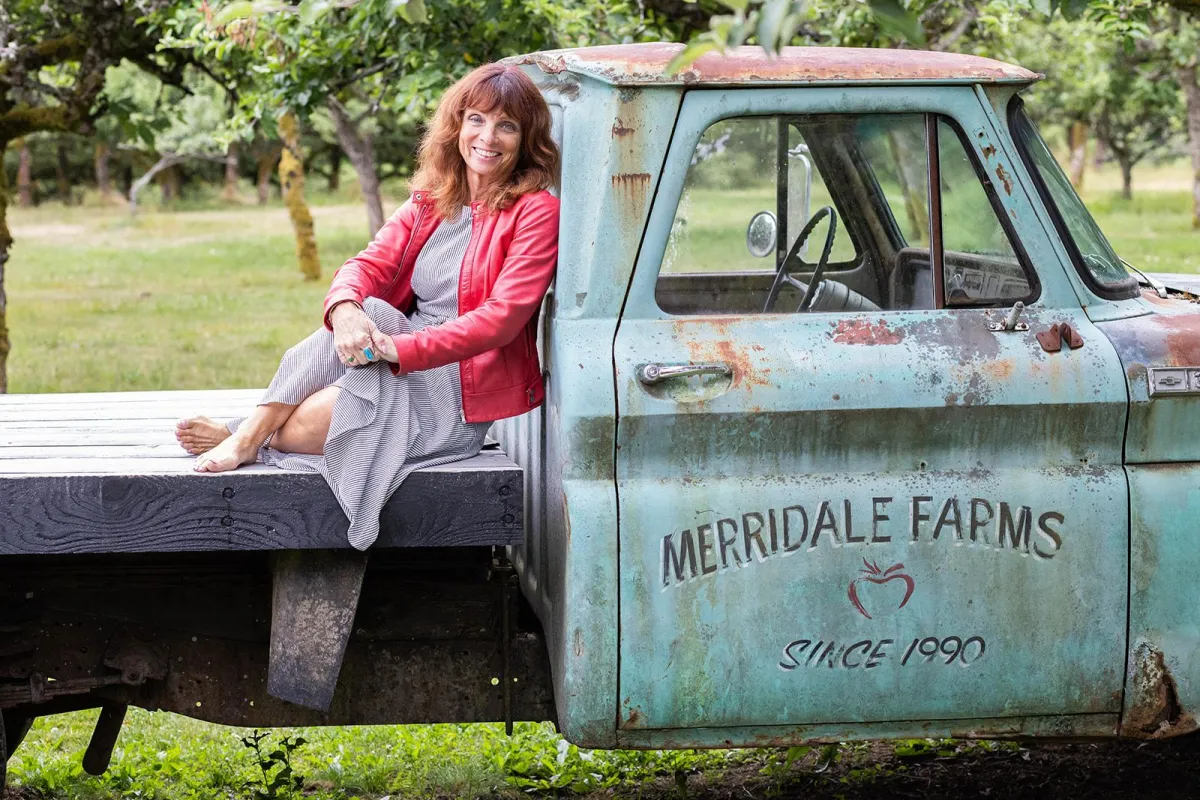 Janet Docherty, owner of Merridale Cidery & Distillery sitting on their vintage truck in their apple orchard