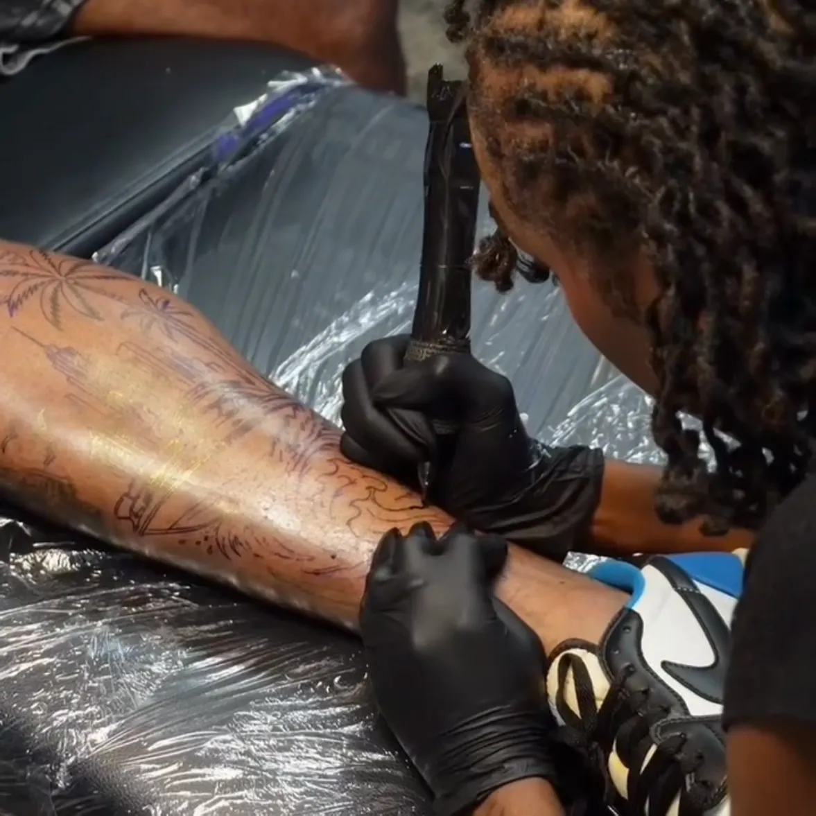 Nishay tattooing a custom black-and-grey leg piece at her private Austin studio