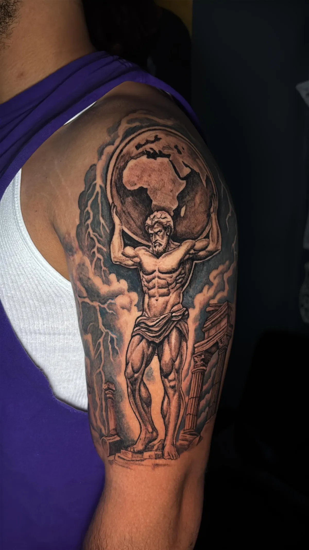 Atlas tattoo Black and grey realism tattoo of Atlas holding the world on an upper arm
