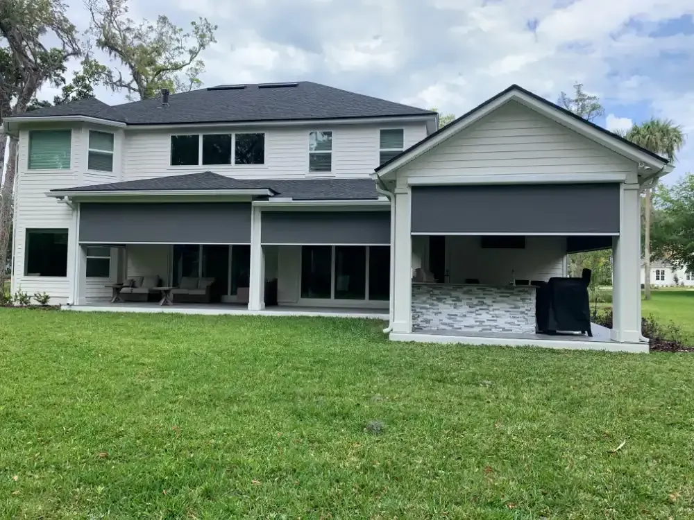 Motorized retractable screens fully deployed on two-story St. Augustine FL home rear patio and lanai providing sun protection, wind blocking, and insect control for year-round outdoor living