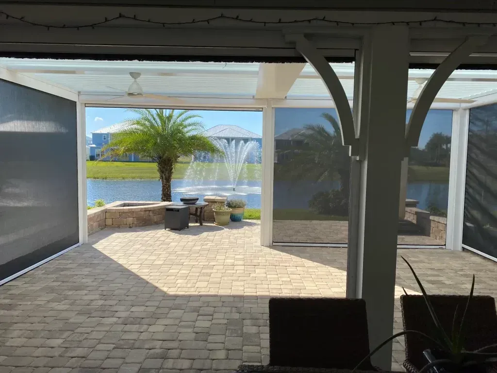 Storm-rated rolldown hurricane shutters installed on Jacksonville Florida coastal home patio overlooking waterfront with paver deck and palm trees showing deployed wind-certified protection