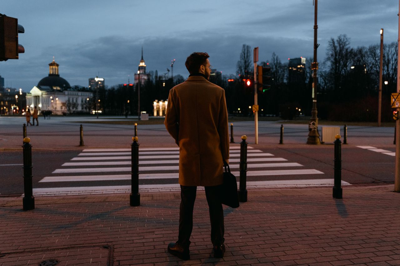 Executive standing at a city crosswalk at dusk, reflecting on identity, success, and the challenge of choosing a new direction.