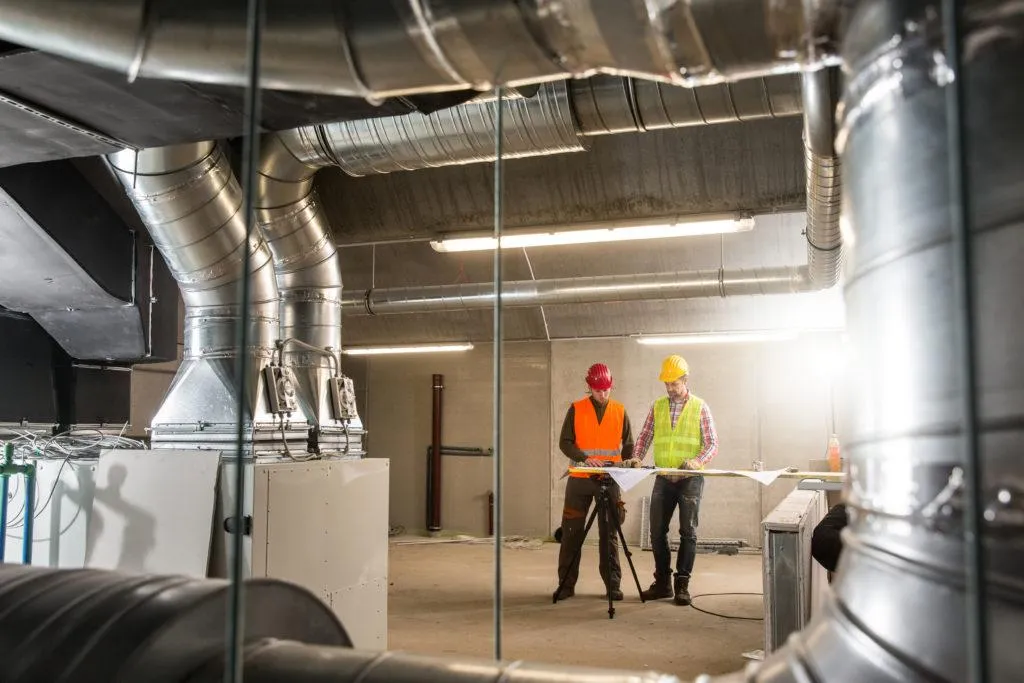 construction workers reviewing blueprint, coi tracking construction, automated COI tracking software