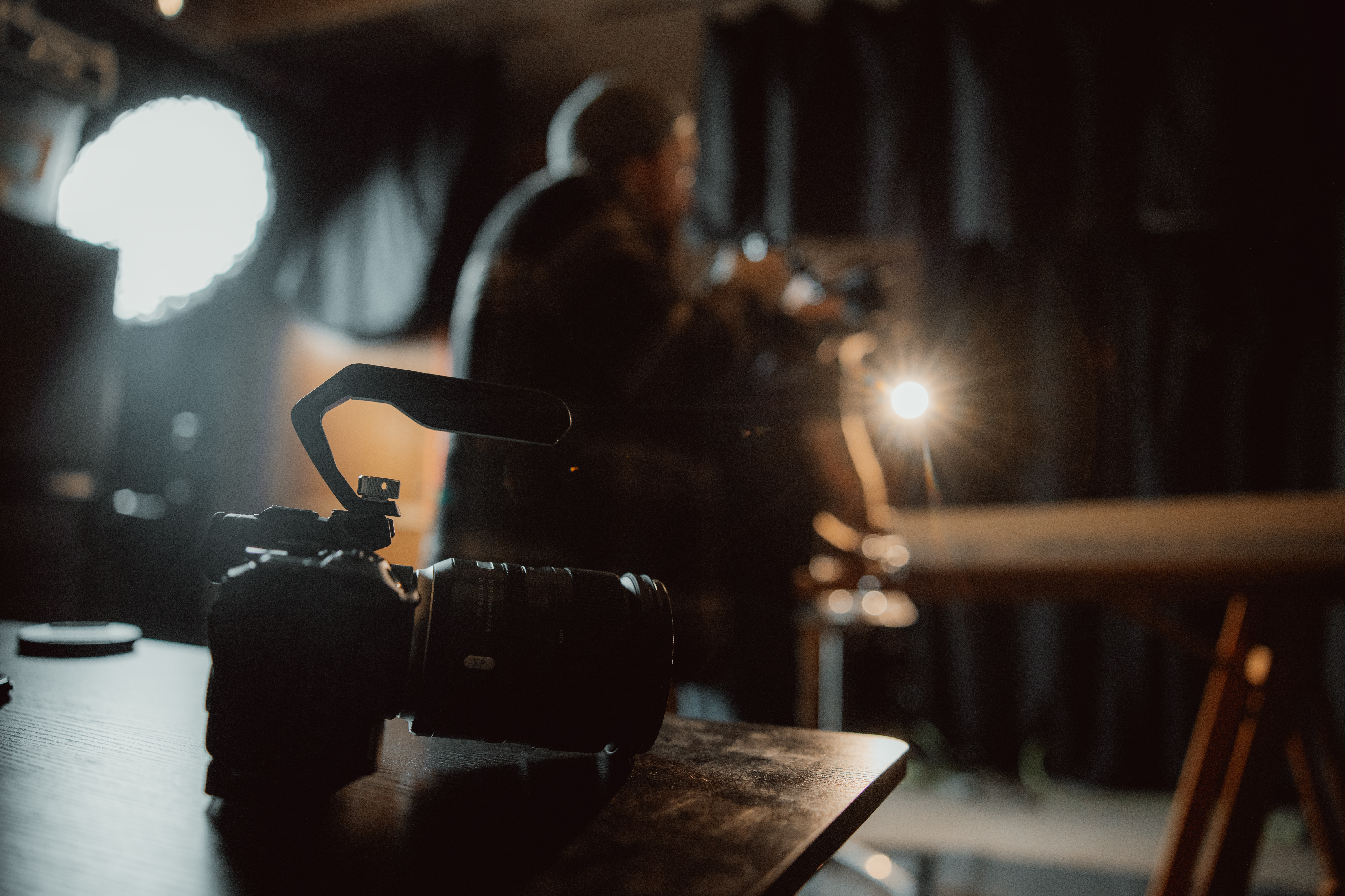 camera sitting on table while video production and photography happening on set in background
