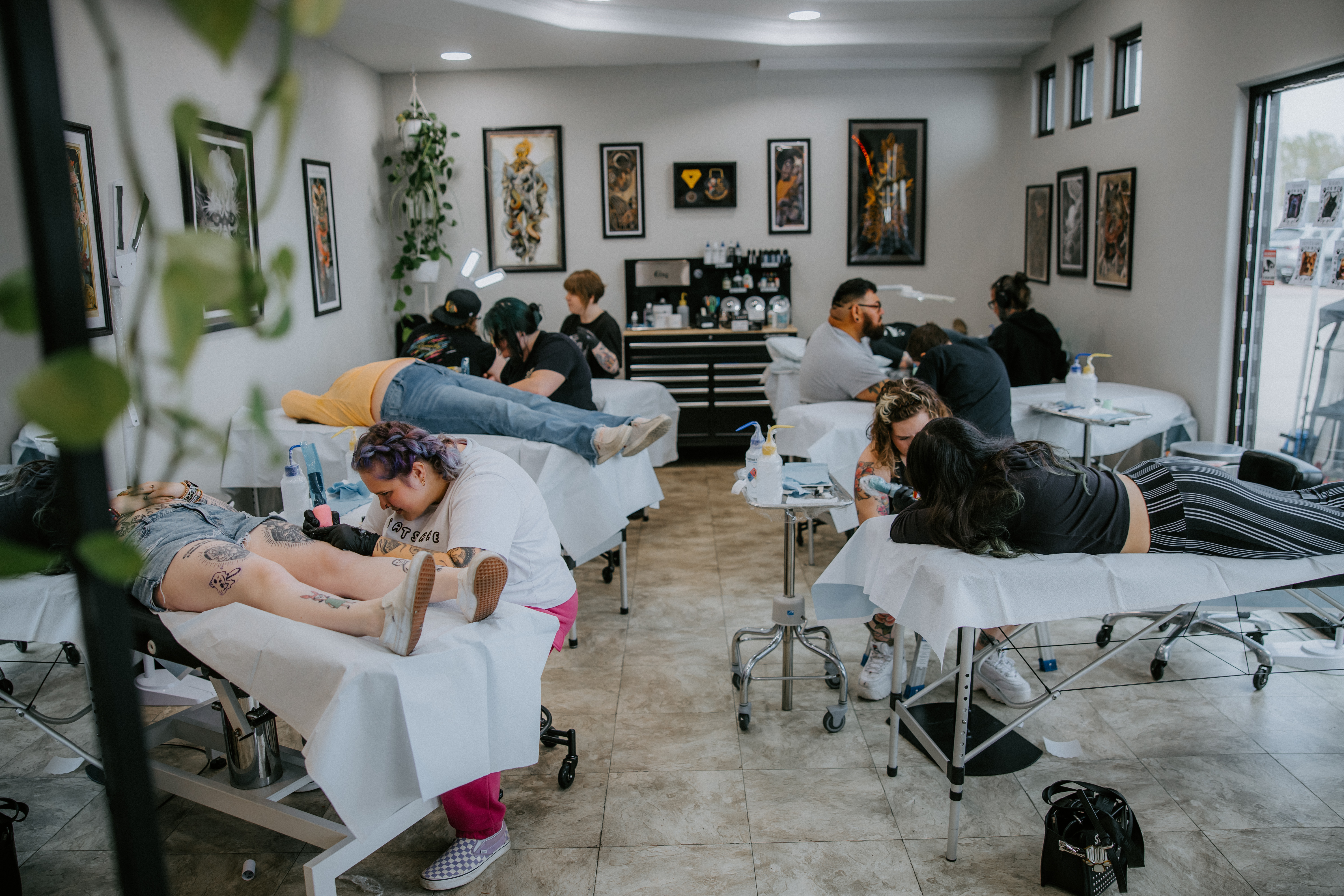 tattoo artists working at a busy shop doing walk in tattoos