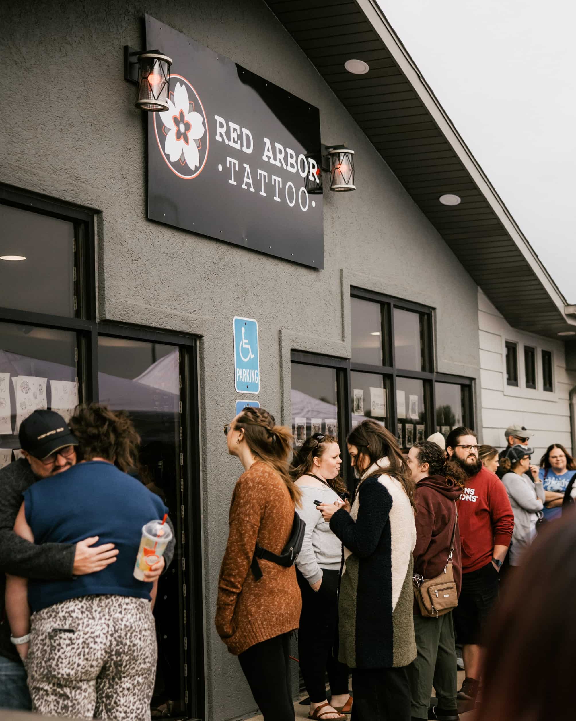 line of people waiting outside red arbor tattoo shop for walk in tattoos